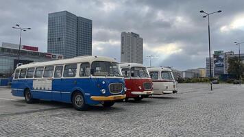 Warsaw, Poland. November 01, 2024. Three vintage buses parked in a row in a city setting. The buses are different colors blue, red, and white. They have a classic design with rounded edges and large photo