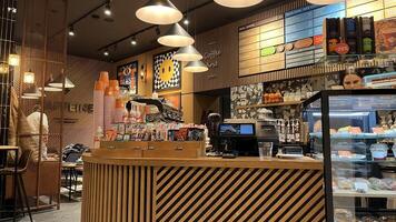 Kaunas, Lithuania. November 15, 2024. A modern coffee shop with a wooden counter, glass display case, and coffee machines. The walls feature colorful artwork. photo