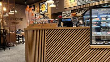 Kaunas, Lithuania. November 15, 2024. A warm and modern coffee shop with a wooden counter, glass display case, and coffee machines. The walls feature colorful artwork. photo