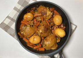 Saute soy sauce chicken or Ayam Kecap with carrots and hard-boiled eggs, served in a black pan. Perfect for recipes, articles, catalogs or any commercial purpose. With copy space. Top view photo