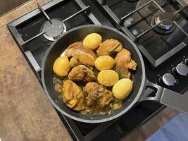 Saute soy sauce chicken or Ayam Kecap with hard-boiled eggs, served in a black pan on the stove. Perfect for recipes, articles, catalogs or any commercial purpose. photo