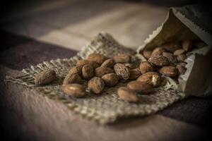 A heap of tasty almonds in a bag on a wooden table photo