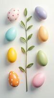 Brightly painted Easter eggs in pastel shades and polka dots arranged with a green branch on a white background, Sustainable, zero waste Easter decor. DIY gifts for Easter photo