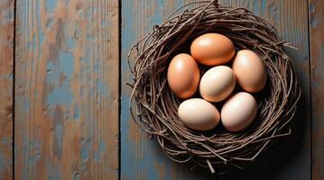 Six eggs neatly placed in a twig nest on a rustic wooden surface with a painted blue texture. Mockup, template for Easter for copy space. photo