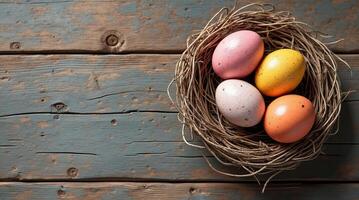 Four colorful speckled eggs in a nest, placed on a rustic wooden background. Concept of Easter, nature, and spring. Mockup, template for Easter for copy space. photo