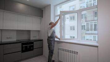 Builder in uniform makes quality control of windows installation in a new apartment. The concept of construction and repair. video