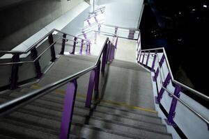 Walkway downward stair at night with light bulb illuminated destination and shadow with dark background building photo