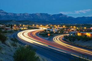 City lights illuminate winding highway near mountains at dusk photo