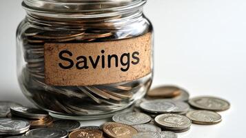 Saving coins in a glass jar labeled for financial goals at home in soft, ambient light photo