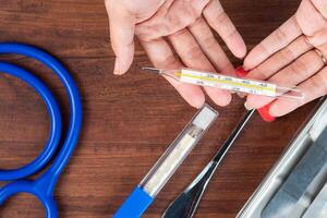 Hands Exchanging a Thermometer in a Medical Setting photo