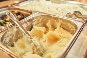 A self-service restaurant where the dishes are served by the customer himself. Close-up of whipped mashed potatoes in a metal tray with space for copying photo
