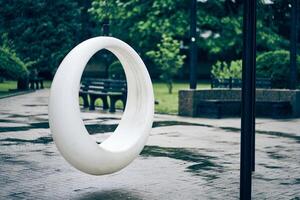 White round swing in cloudy weather. A recreation area in the park. Rocking chairs in the park in summer with space to copy photo