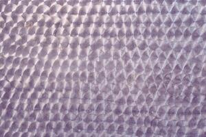 A holographic surface of light lilac color with space for copying. Iridescent film texture photo