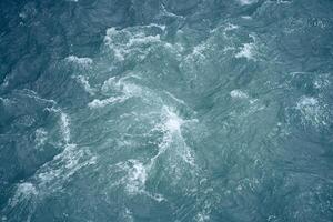 Beautiful background with blue water and a place to copy. Close-up of raging waters. Ripples and waves on the water. photo