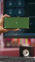 Vertical Woman using green screen smartphone to learn how to use AI LLM chatbot on computer screen in home office. Person watches tutorial on mockup phone about artificial intelligence chatbots, camera B video