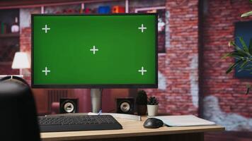Isolated screen mockup PC on home office desk with stationary items and headphones on, surrounded by plants. Chroma key computer display in loft with shelves filled with books in background video