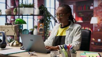 Portrait of smiling student at home browsing internet on notebook, doing homework, researching information online. Cheerful girl in apartment reading articles on laptop for school tasks, camera B video