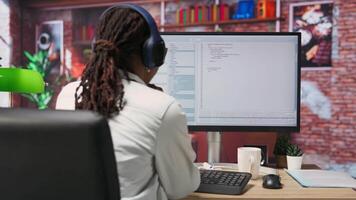 Excited programmer wearing headphones testing code on PC, clapping hands after seeing positive result. Upbeat woman at home overjoyed after fixing errors in application, listening music, camera B video