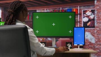 Student in living room browsing internet on isolated screen computer and tablet, doing homework. African american woman in apartment reading articles on chroma key PC and device for school tasks video
