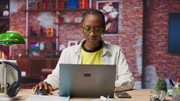 Portrait of happy teleworker using laptop in home office to write emails. Joyful remote worker typing on notebook, composing documents in order to deliver finalized project paperwork, camera B video
