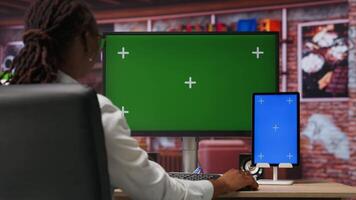 Freelancer in home office using green screen PC and mockup tablet to work on job tasks. Teleworker using chroma key computer monitor and isolated screen device to do job online video
