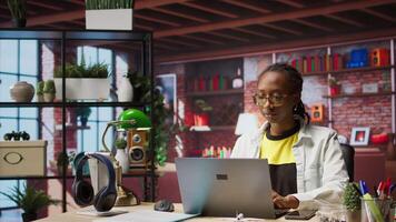 Portrait of happy teleworker using laptop in home office to write emails. Joyful remote worker typing on notebook, composing documents in order to deliver finalized project paperwork, camera A video