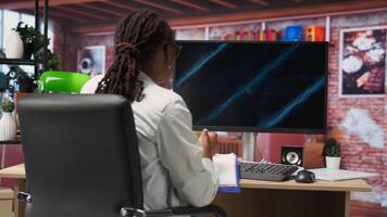Student doing academic research on internet to gain financial knowledge useful for career development, taking notes. African american woman in online class doing courses, writing down info, camera B video
