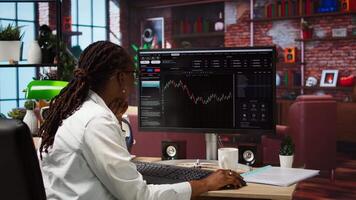 Day trader using PC, purchasing stocks that might perform well and selling ones that might drop in value. Forex trader browsing though stock exchange portfolio pages at computer desk, camera A video