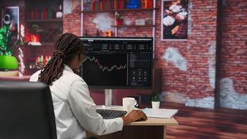 Day trader using PC, purchasing stocks that might perform well and selling ones that might drop in value. Forex trader browsing though stock exchange portfolio pages at computer desk, camera B video