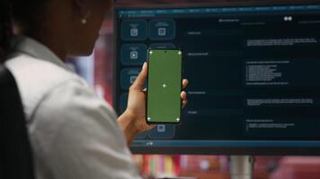 Woman at home holding mockup smartphone asks questions to AI LLM virtual assistant answering prompts. Person with chroma key phone receiving information from artificial intelligence GPT, camera B video