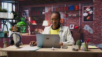 Worker at home starting job shift, opening laptop to analyze data at desk, compiling analytical reports. Remote employee beginning tasks, using notebook device, writing down information, camera B video