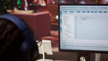 Engineer in home office looking at UI on computer monitor, typing and executing programming code. Close up of person using coding application to write and test code in modern apartment, camera A video