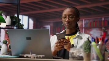Happy woman relaxing in apartment, texting friends on smartphone, enjoying leisure time. Smiling person taking break from studying to talk with mates on social media website using phone, camera B video