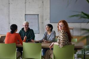 A young, diverse business team sitting together in a modern office, exchanging ideas and business plans, fostering collaboration and innovation for future success. photo