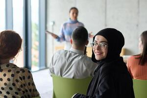 A diverse group of business professionals sits attentively in a modern office, actively participating in a training session led by an instructor, focusing on the latest technological advancements in photo