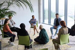 Corporate business team meeting with a manager or coach. Group of happy diverse, multiracial people sitting in a circle photo