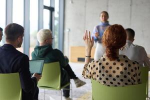 A diverse group of business professionals sits attentively in a modern office, actively participating in a training session led by an instructor, focusing on the latest technological advancements in photo