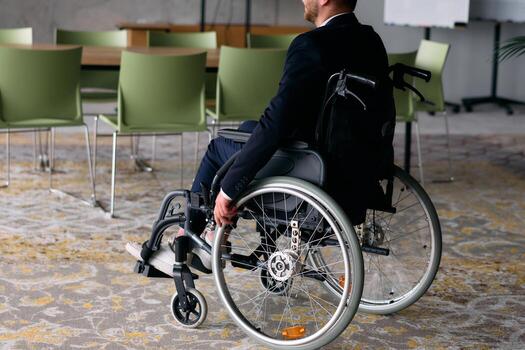 A director in a wheelchair sitting alone in an empty office, deeply reflecting on business strategies and decisions, contemplating the path forward with focused determination. photo