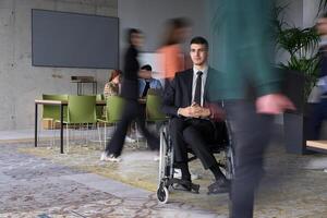 A businessman in a wheelchair navigating through a busy office, surrounded by his colleagues who are actively engaged in their work and collaboration photo