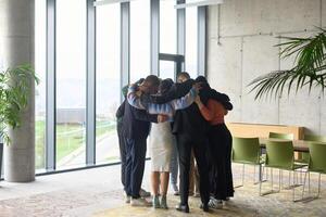 A diverse group of professionals standing in a supportive circle, embracing each other in a modern office space filled with natural light. photo
