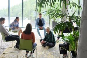 Corporate business team meeting with a manager or coach. Group of happy diverse, multiracial people sitting in a circle photo