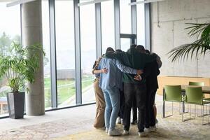 A diverse group of professionals standing in a supportive circle, embracing each other in a modern office space filled with natural light. photo