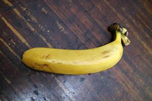 One big ripe yellow banana is placed on a wooden table photo