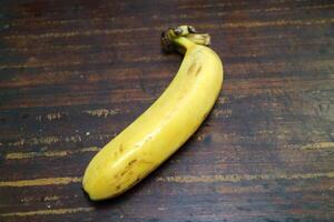 One ripe yellow banana is placed on a wooden table photo