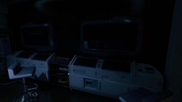 Dimly lit control room featuring empty monitors and a swivel chair video