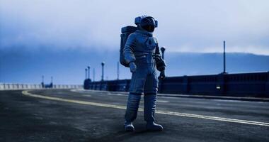 Astronaut standing on an empty road under a cloudy sky at twilight video