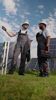 Indian and Caucasian workers discussing solar panel maintenance video