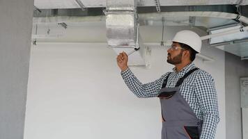 Indian worker installing ventilation system in office building video