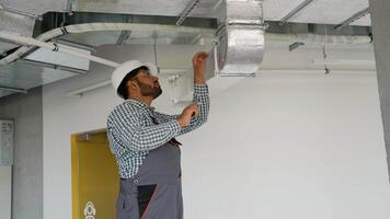 Indian worker installing ventilation system in office space video