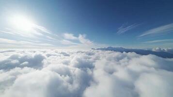 View above clouds with bright sun and mountain peaks in background photo